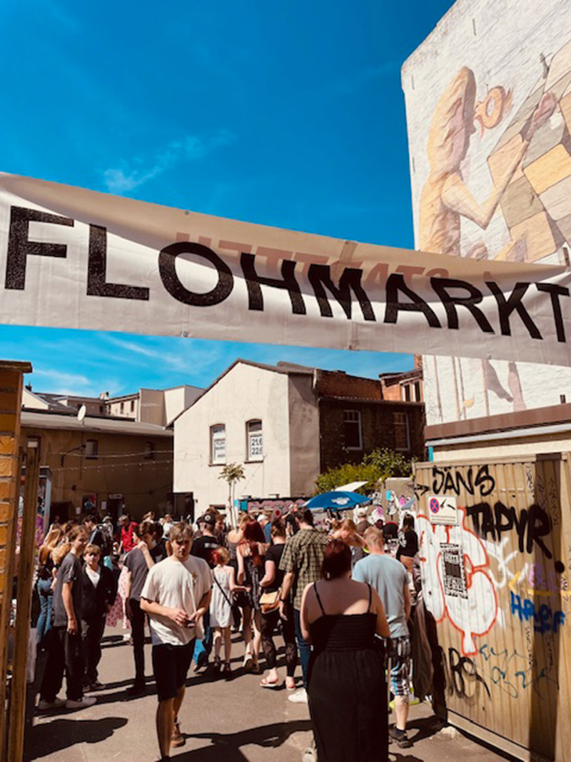 Flohmarkt Friese 7 banner mit der aufschrift flohmarkt über dem eingang zum gelände der friese 7 im medizinerviertel in halle im hintergrund viele besucher